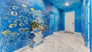 A hallway with a blue mural of fish, a potted plant, and a door.