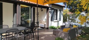 An outdoor patio with a table and chairs, a wicker sofa, and a yellow umbrella.