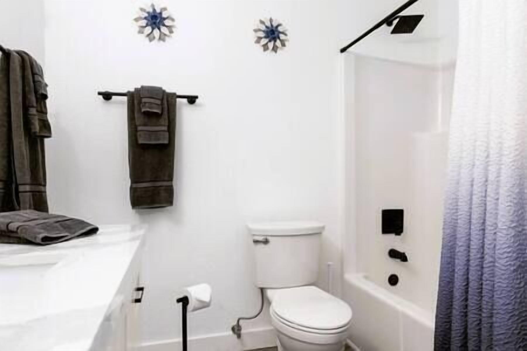 A bathroom with a toilet, a towel rack with towels, and a shower area.