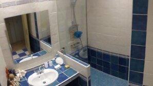 A bathroom with a sink, mirror, and shower. - Apartment with terrace overlooking the lake, a stone's throw from the port (Mèze)