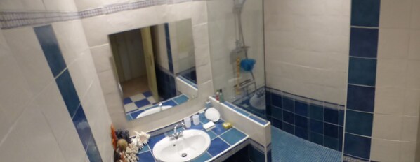 A bathroom with a sink, mirror, and shower.