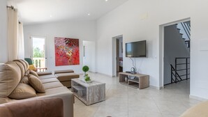 Un salon moderne comprenant un canapé, une table basse, un téléviseur et un escalier.