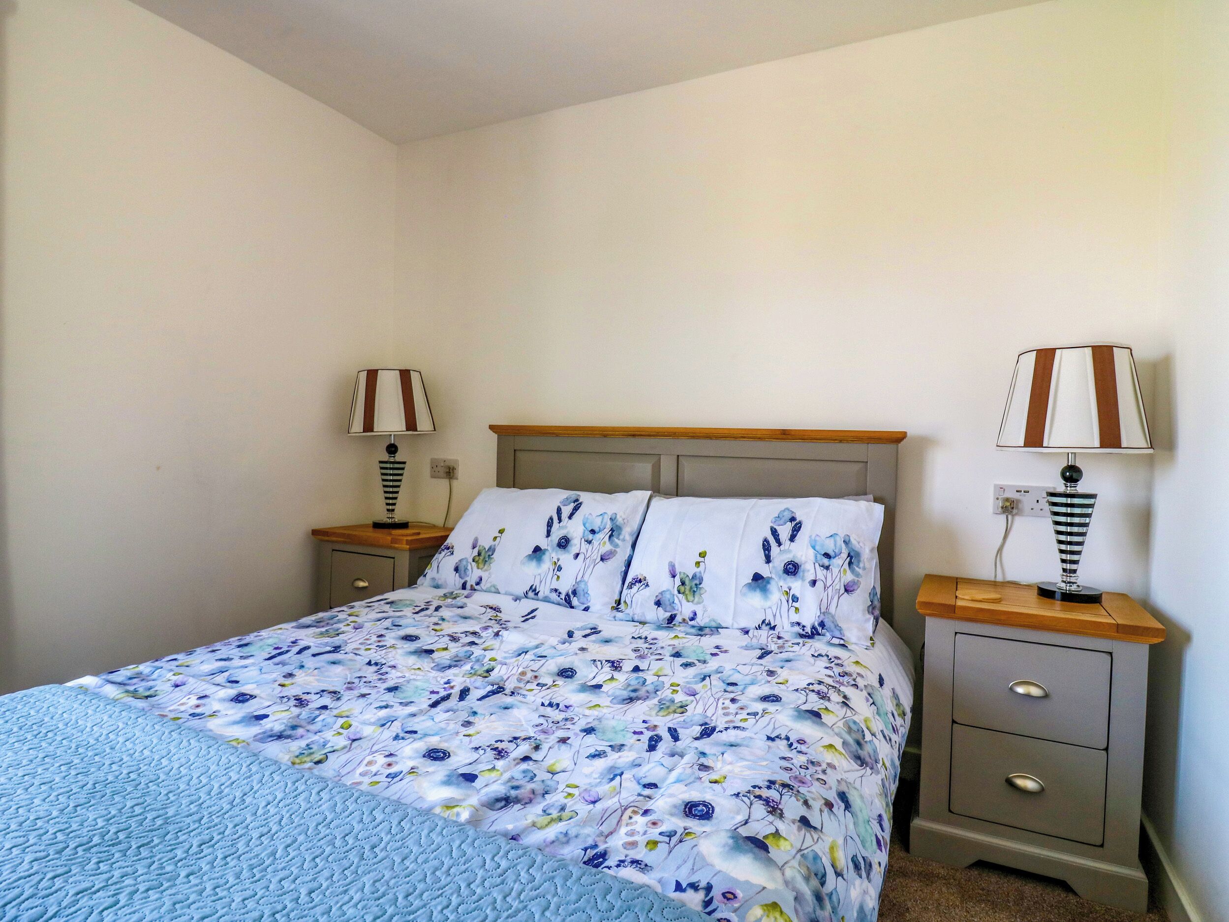 A bedroom with a bed, two bedside tables, and two lamps.