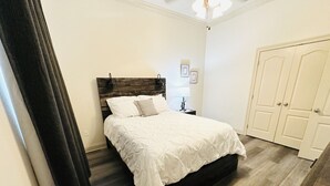 Une chambre à coucher avec un lit, une table de chevet, une lampe et une armoire.