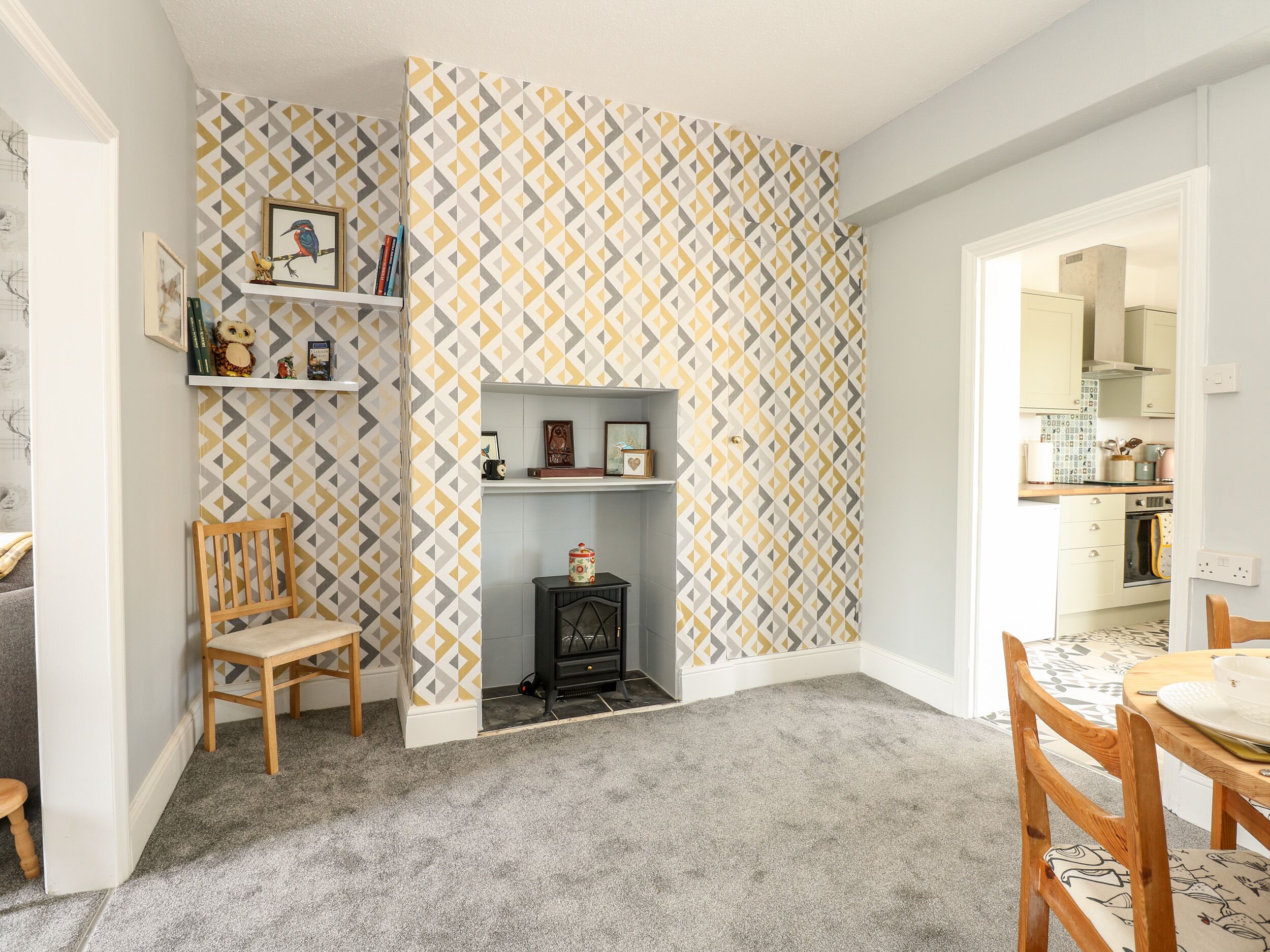 Une pièce chaleureuse avec un papier peint à motifs, une cheminée, une chaise en bois et une table à manger.
