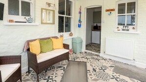 Ein gemütliches Zimmer mit einem Korbssessel, einem kleinen Tisch und einem gemusterten Boden.