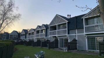 Houses with gabled roofs and front porches sit behind a wooden fence in a suburban setting.