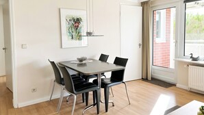 A dining area with a table, chairs, and a pendant light. - North Sea Residence App 23 Westerland (Westerland)