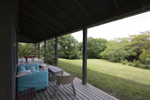 Un espace extérieur aménagé, abrité et doté d’une terrasse en bois, d’un canapé et d’une table.