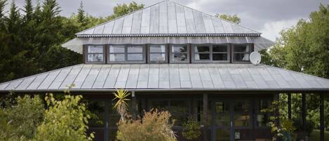A modern building with a sloped roof, large windows, and a satellite dish.
