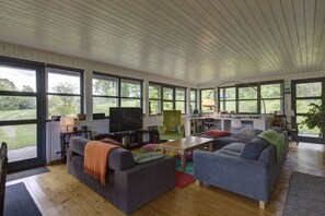 Un salon spacieux doté d’une grande télévision, de sièges confortables et d’un espace bureau.