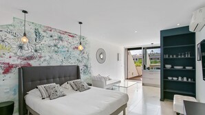 A modern bedroom with a large bed, a glass coffee table, and a decorative wall mural. - Naturist Village - Le Diamond X Héliopolis Luxe, Naturist Village (Agde)