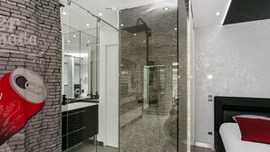 Une salle de bain moderne avec une douche à parois de verre, un grand miroir et une affiche rouge de Coca-Cola.