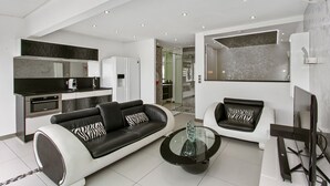 Un salon moderne avec un canapé noir et blanc, une table basse en verre et un téléviseur à écran plat.