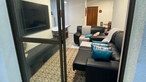 Una sala de estar con un sofá, una mesa de centro y un televisor montado en la pared.