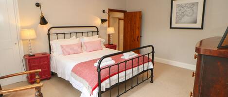 A neatly arranged bedroom with a single bed, bedside tables, a chair, and a wooden wardrobe.