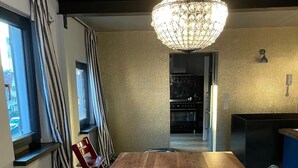 Une cuisine moderne avec une table en bois, un lustre et une vue sur le salon.
