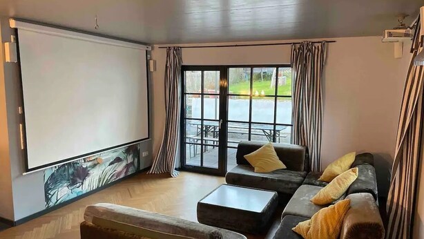 Un salon confortable avec un ensemble de canapés, une table basse et un grand écran pour regarder des films ou la télévision.