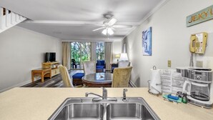 A hotel room with a kitchenette, dining area, and a view of the outdoors. - Villa 452 - lovely condo just steps away from pool and beaches (Jekyll Island)