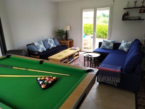 Une table de billard avec des billes, un canapé, une table basse et une lampe.