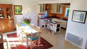 A spacious kitchen with a dining area, featuring a wooden table, chairs, and a red rug. - Family home- Charm of the countryside and  the wildness of the Ocean. (Plovan)