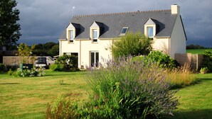 A two-story house with a sloped roof, a front door, and a garage. - Family home- Charm of the countryside and  the wildness of the Ocean. (Plovan)