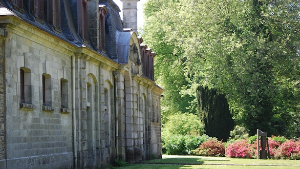 A historic building with a stone facade, arched windows, and a garden with trees and shrubs. - Family home- Charm of the countryside and  the wildness of the Ocean. (Plovan)