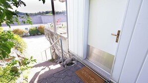 Un paillasson devant l’entrée d’un immeuble, avec une rambarde métallique et une porte.