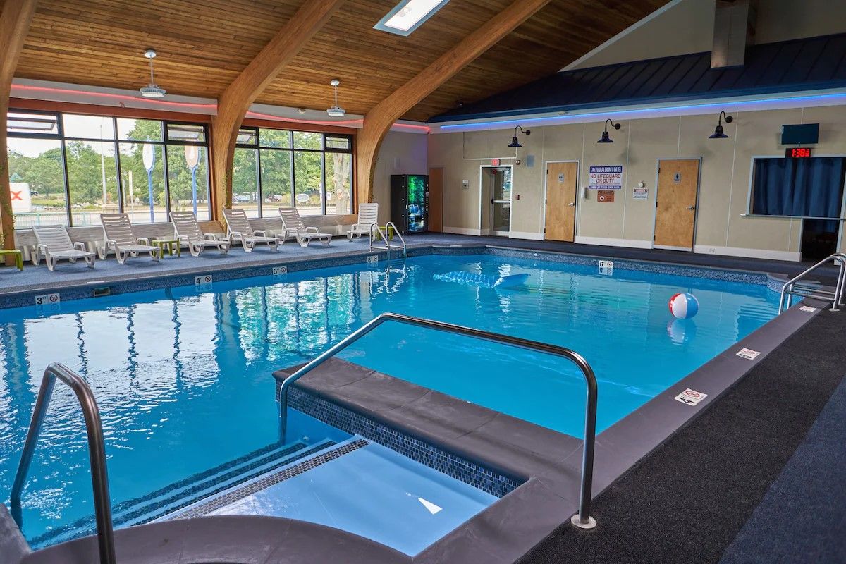 Piscina interna com água cristalina, plataforma de mergulho e espreguiçadeiras.