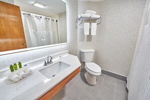 Un baño con lavamanos, espejo, inodoro y toallero.