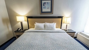 A hotel room with a bed, two bedside tables, a framed picture on the wall, and a window with a view.