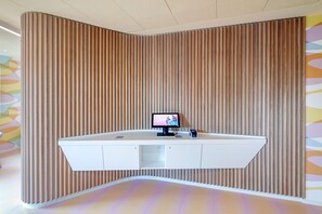 Een receptiebalie met een flatscreen televisie, een klein digitaal klokje en een kaartlezer.