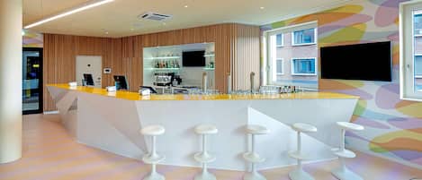 A modern bar area with a curved counter, bar stools, and a television screen.