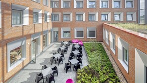 Un patio con mesas al aire libre, un edificio de ladrillo y un jardín en la azotea.
