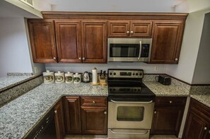 Kitchen features a stovetop with digital controls, a microwave, and a black oven.