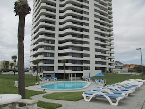 Relax by the pool surrounded by lush greenery and palm trees.