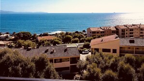 A coastal residential area with buildings, a view of the sea, and a distant ship. - AJACCIO STUDIO VUE MER 200 M PLAGE (Ajaccio)
