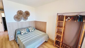 A bedroom with a bed, a wooden wardrobe, and a wall-mounted shelf. - AJACCIO STUDIO VUE MER 200 M PLAGE (Ajaccio)