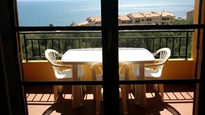A balcony with a white table and chairs, overlooking a coastal view. - AJACCIO STUDIO VUE MER 200 M PLAGE (Ajaccio)