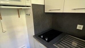 A compact kitchen with a microwave, stove, and white cabinets. - AJACCIO STUDIO VUE MER 200 M PLAGE (Ajaccio)
