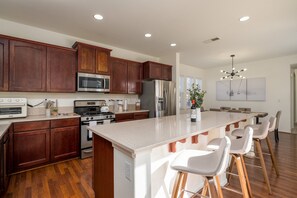 Enjoy cooking in this well-equipped kitchen with a large island, stainless steel appliances, and a spacious dining area.