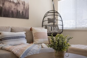 Relax in this serene living space, featuring a cozy sofa, a round table, and a unique birdcage decoration.