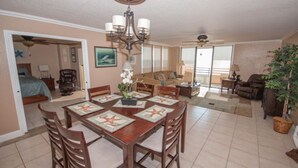 A spacious living area with a dining table set for six, a large window with a view, and a ceiling fan. - Spacious 9th floor Horizons Oceanfront 2/2 (Daytona Beach)