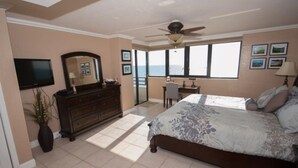A bedroom with a bed, dresser, TV, and a balcony with a view. - Spacious 9th floor Horizons Oceanfront 2/2 (Daytona Beach)