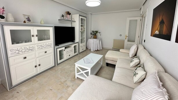 A modern living room with a flat-screen TV, white furniture, and a painting on the wall. - La Posada Manchega House 2 (Consuegra)