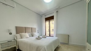 A bedroom with a bed, nightstands, a radiator, and a window with curtains. - La Posada Manchega House 2 (Consuegra)
