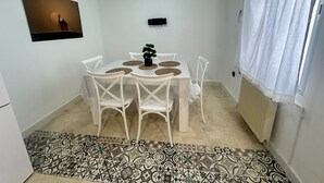 A small dining area with a table, chairs, a potted plant, and a patterned rug. - La Posada Manchega House 2 (Consuegra)