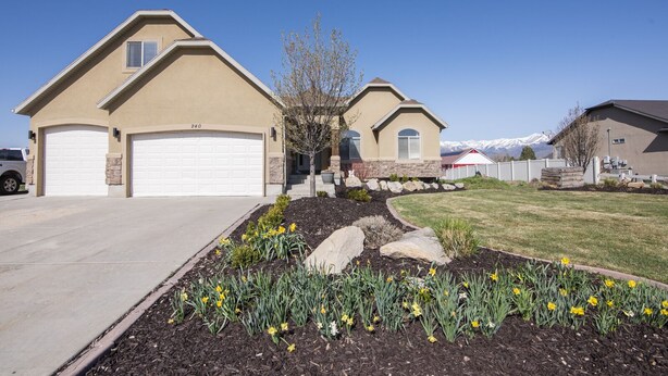 A residential area with two houses, each with a garage and a driveway. There are flower beds with daffodils in the front yard. - Heber House, 20 min to Park City! Close to downtown Heber. (Heber City)