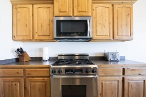 A kitchen with wooden cabinets, a stainless steel stove, a microwave, and a toaster.