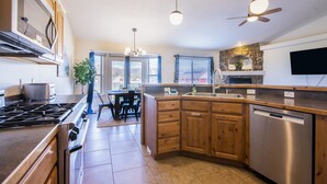 A modern kitchen with a central island, stainless steel appliances, wooden cabinets, and a dining area with a view. - Heber House, 20 min to Park City! Close to downtown Heber. (Heber City)
